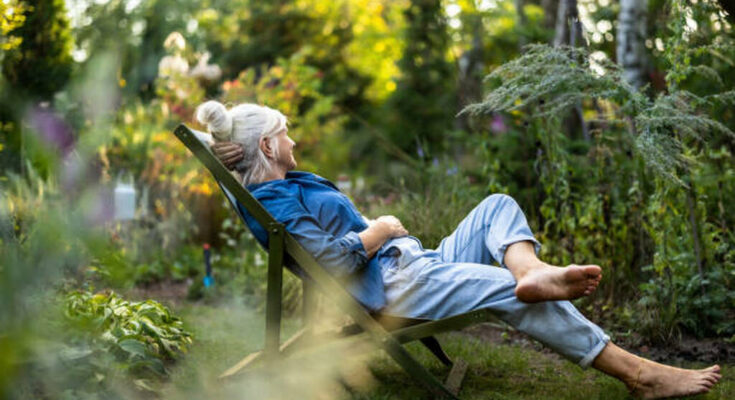 Mature woman relaxing in deckchair in her garden